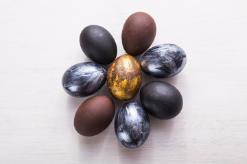 Holidays, traditions and Easter concept - Dark stylish easter eggs on white wooden background.