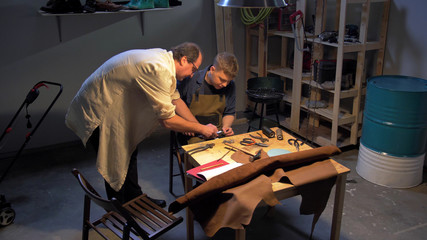 Master helps man to make a shoe in a workshop