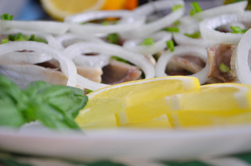 Herring fillet with salt, pepper, herbs, onion and lemon on black plate on white background. top view. healthy food