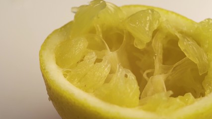 Squeezed lemon lies on a white table. The white table is spinning, or the camera is spinning around the table.