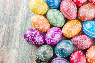 Variety of colorful handmade scratched easter eggs on wooden table
