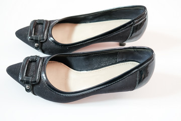 Side on view of a pair of ladies black heeled shoes with a square buckle on the front on a plain white background