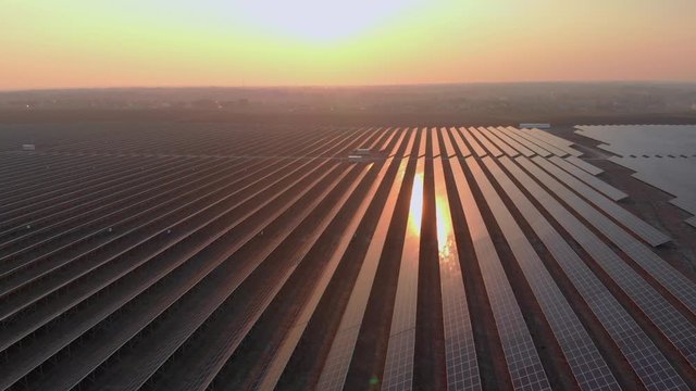 Aerial drone view into large solar panels at a solar farm at bright sunset. Solar cell power plants. footage video 4k.