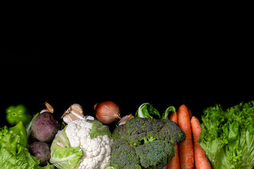 Fresh vegetables on black background. Raw organic vegetables and healthy food concept. Background layout with horizontal text space.