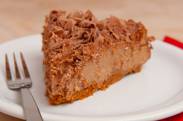 Brown chocolate slice of cake with curly flakes