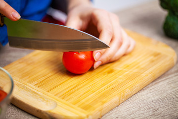 Closeup of woman slices tomato for diet salad