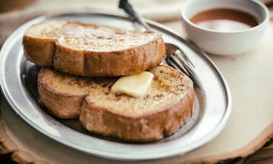 Two pieces of french toast with butter and syrup.