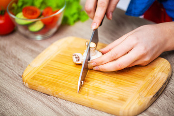 Closeup of woman slices mushrooms for diet salad