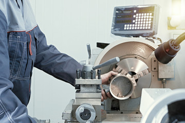 A worker drills a steel part