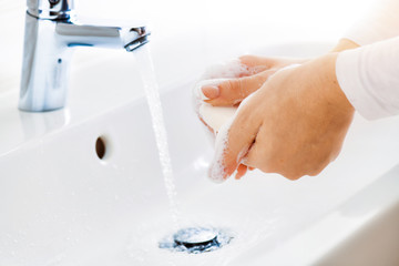 Woman use soap and washing hands under the water tap. Hygiene concept hand detail.