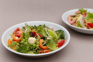 white deep plates with fresh salad ingredients mixed with sauce placed on an attractive background. A place for a menu, banner or advertisement