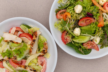 white deep plates with fresh salad ingredients mixed with sauce placed on an attractive background. A place for a menu, banner or advertisement