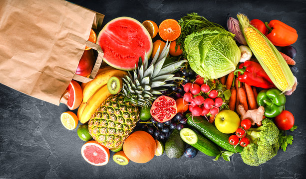Vegetables and fruits healthy food dropping out of paper bag on darkbackground. Top view vegetable photo, copy space fot text.