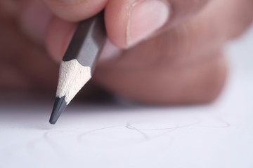 Close up of male hand writing with pencil on paper