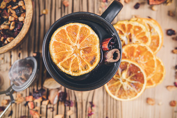 Fruit tea with cinnamon and dried berries in cup - teacup on wooden table.