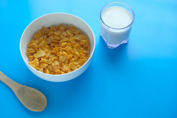 Tasty crispy corn flakes with milk on blue background.