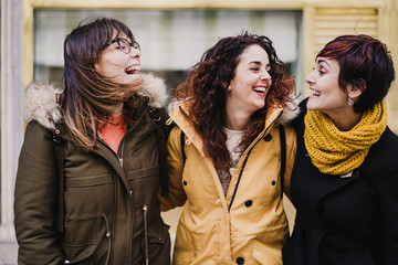 group of friends using mobile phone outdoors in the street. Happy women smiling. lifestyle and...
