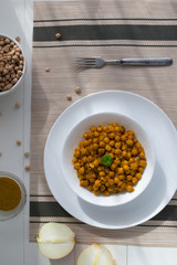 Braised chickpeas with onions and curry in a white plate on a light background. Vegetarian food. Healthy eating