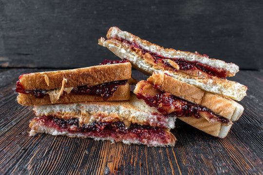 messy peanut butter and jelly sandwiches cut in half in stack