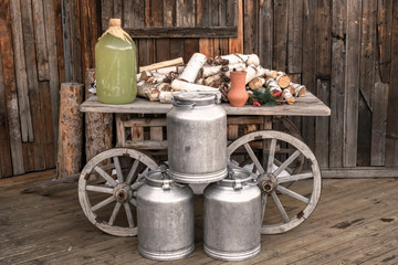 Wooden retro cart with wateringcans logs and wooden background. Countryside concept.