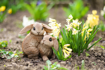 gypsum figurine of hares standing in the garden near hyacinths