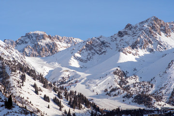 Shymbulak gorge and mountains with ski slopes. Winter mountains landscape. Nature, travel, adventure, hiking.
