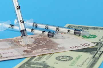Syringe needles in a map of Europe on paper money. The spread of the virus, disease, epidemic. Search for a vaccine and treatment.