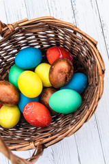 Many Easter colored plain eggs. A set of homemade eggs for Happy Easter holiday on a white wooden background. Boiled cooked eggs in a wicker basket top view