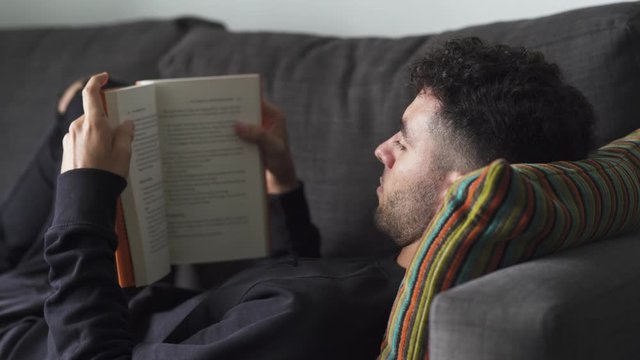 Caucasian Male reading a book on the couch