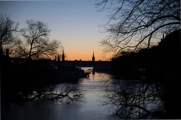 Morning view over the old town Gamla Stan in Stockholm with churches from the river passage Pålsundet in the district Södermalm, framed by trees in silhouette