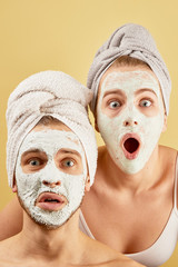 Young friends guy and girl with funny expressive emotions, towel on head and face mask isolated on...