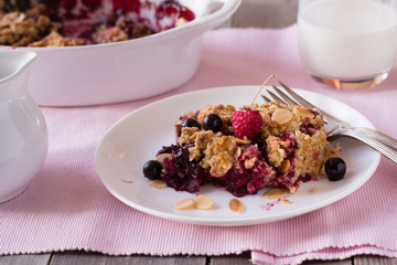 Berry crumble in white plate on pink napkin