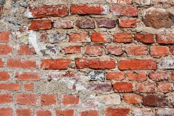 Ancient red bricks wall with old natural stones. Textured brickwork. Old rustic wall with bricks,cement and big natural stone. 