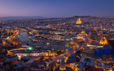 Panoramic view of Tbilisi city from NArikala fortress after the sunset during blue hour. Light trails of traffic and romantic Georgia concept. 2020