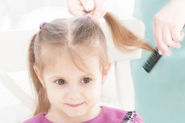 Naklejka premium hands of mother combing little smiling girl