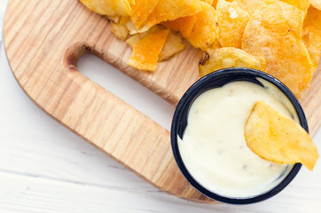 Potato chips and dip on wooden board