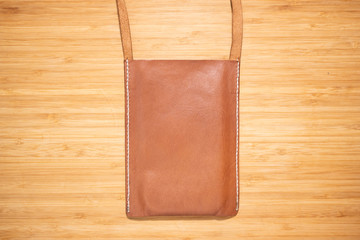 Leather mobile bag on wooden table.