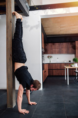 Sports exercises at home, the men performs a handstand