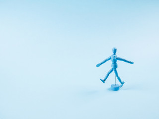 Blue wooden human marionette dummy walking alone on monochrome backdrop