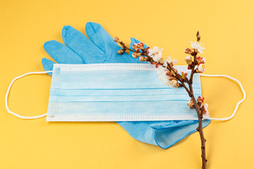 The concept of comparing prevention and health with spring in nature. Means of preventing viral diseases. Medical mask and rubber gloves on a yellow background .  Corona virus.