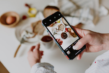 girl photographs breakfast on an smartphone