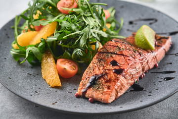 Hot smoked salmon with arugula salad, cherry tomato and orange. Healthy eating.