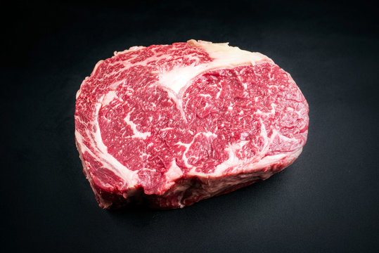 Raw dry aged wagyu entrecote beef steak as closeup on a black background with copy space