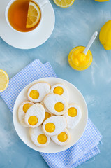 Easter cookies in the form of Easter egg with powdered sugar and lemon cream on a white plate on a light blue concrete background. Vertical orientation, Copy space. Top view.