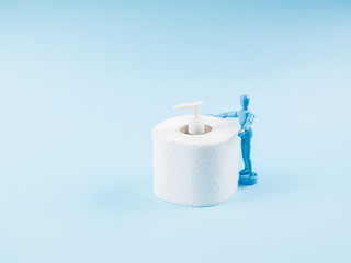 Blue marionette hugging toilet paper roll and sanitizer gel during Covid-19 pandemic on blue abstract background. Panic concept in coronavirus quarantine