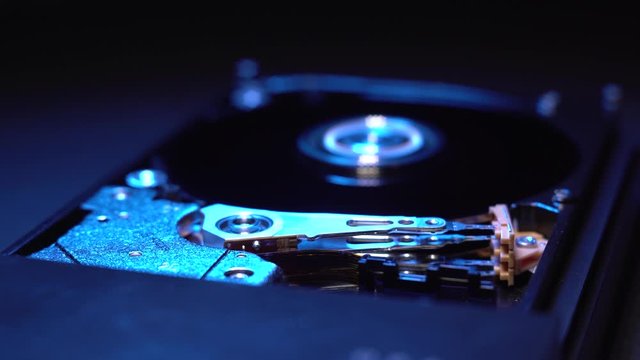 Inside the hard drive or hard-disk. Storage for information, the head of hard drive moves and reads information from the media. Macro footage in blue color.