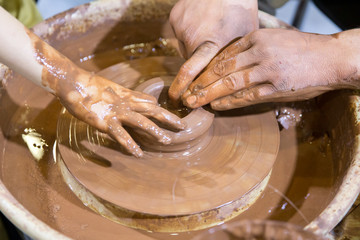 Hands on a pottery wheel. Clay potter creating on the pottery wheel
