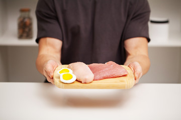 Athletic man holding a board with meat for proper nutrition of the athlete
