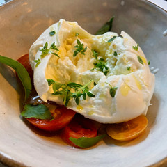 Fresh buffalo mozzarella on tomatoes with basil, thyme and olive oil 