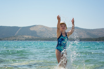 little young girl playing on a beach splashing water in a sea on summer holiday in croatia 